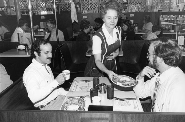 Barbara the waitress serves breakfast to Steve Kimbrough at an unidentified Rennebohm Drug Store restaurant while Albert Friedman drinks coffee and waits for his order.
