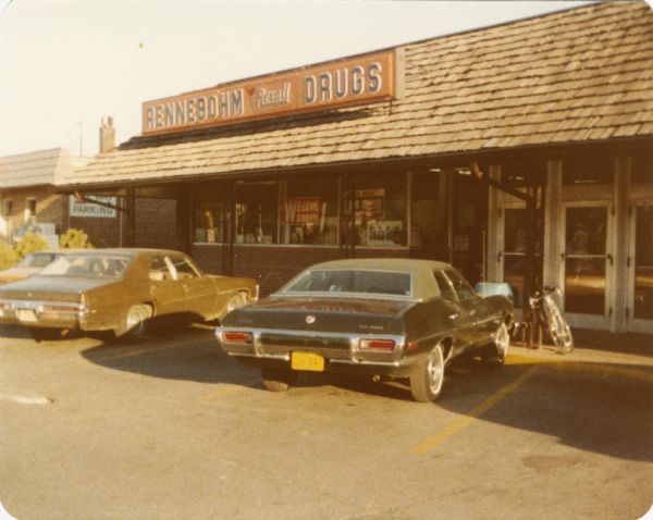 Snapshot of the front Rennebohm Drug Store located at Shorewood Shopping Center, on University Avenue, with several cars parked in front. The snapshot was taken by amateur photographer Steven O. Kimbrough who, with Chuck Patch was engaged in a personal project to eat breakfast at and photograph all of the then-existing Rennebohms.