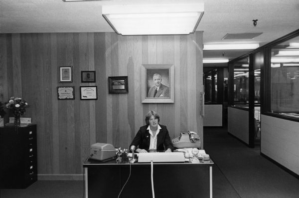 A receptionist is seated at her desk in the Rennebohm home office, 2300 Badger Lane.