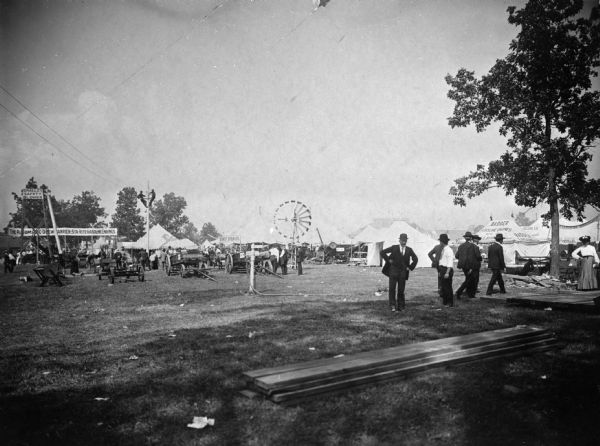 Exhibits of farm equipment and the gasoline engines that would have powered some of them at the Wisconsin State Fair. A Ferris wheel is visible in the background.
