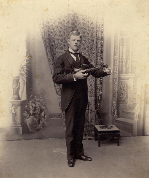 Studio portrait of Emil Buehler holding a violin.