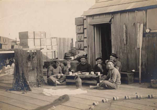 A group of Maine commercial fishermen having lunch on a dock.
