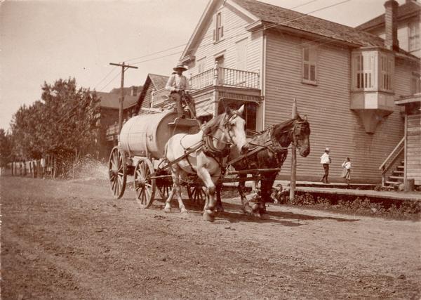 Two horses pull a street waterer. When Main Street was a dirt road, the local merchants paid to have it sprinkled during the summer to keep the dust down.

