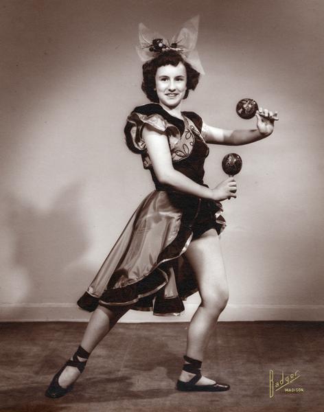 A member of the Kehl family poses in a dance costume holding maracas.