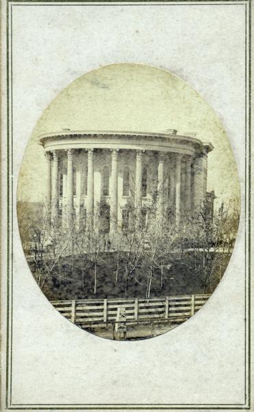 East wing of the third Wisconsin State Capitol building (second in Madison) photographed from the U.S. Hotel building which was located at the corner of East Main and Pinckney Streets. John S. Fuller, the photographer, had a studio located here.