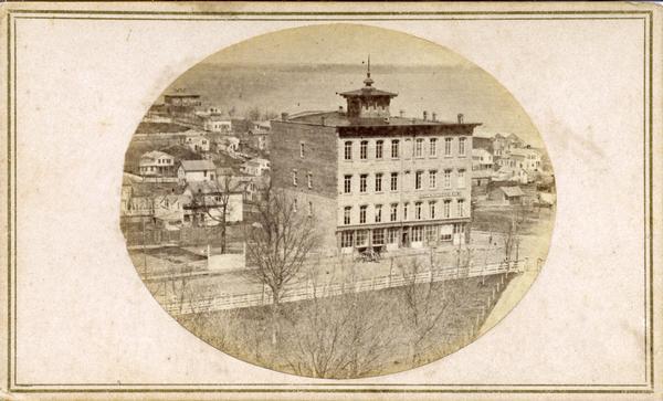 View of East Mifflin Street taken from the Wisconsin State Capitol roof. The building in the foreground, at the corner of East Mifflin and North Pinckney Streets, eventually became the Capitol Hotel and then the Madison Hotel. The Jacobs House, in the upper left, was designed by the same architect who designed the Capitol, and was built for a sister and brother-in-law of Governor Fairchild.