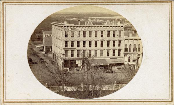 Elevated view of South Pinckney Street and East Washington Avenue from the roof of the Wisconsin State Capitol building. Shows the Wisconsin State Journal building, with the fence surrounding the Capitol Park in the foreground.