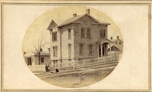 Orsamus Cole residence located at the corner of Pinckney and Gorham streets. Cole was a justice of the Wisconsin Supreme Court beginning about 1855. Three children are standing at the corner of the front yard.