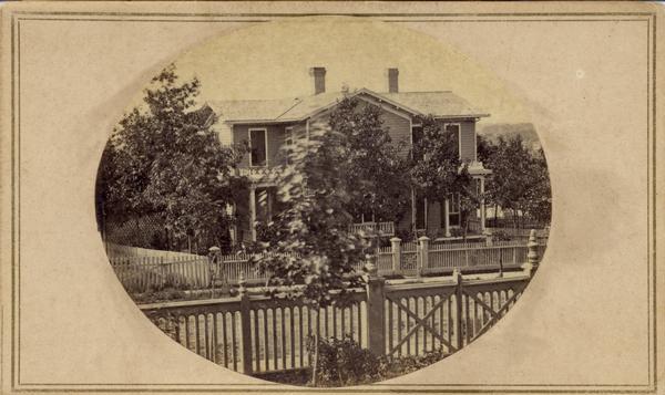 Exterior view of a Madison residence, possibly on Gilman Street. The yard is enclosed by a fence.