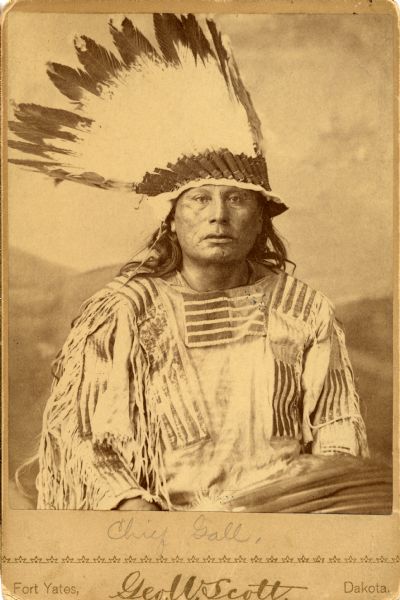 Waist-up studio portrait in front of a painted backdrop of Chief Gall, Sioux Nation, in traditional clothing. Chief Gall was a Judge Advocate General.