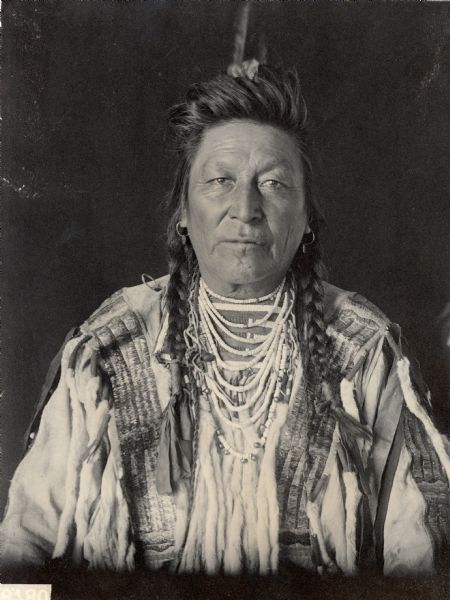 Studio portrait of Chief Yshidiapas or Aleck-Shea-Ahoos (Plenty Coups) in Native Dress with Ornaments. He was part of the Siouan, Crow tribe.