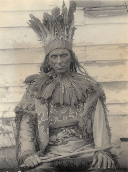 Portrait of William Terrill Bradby wearing a headdress and holding a club. Part of the Algonquian and Pamunkey Tribes.
