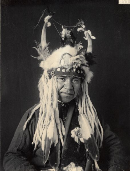 Waist-up studio portrait of William Charley, interpreter, in native dress with horned headdress. Part of Shahaptian and Umatilla Tribes.
