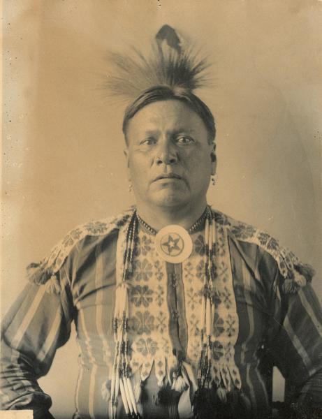 Studio portrait of Chief Charkshepshutsker (Red Eagle), also known as Henry French, in partial native dress with ornaments. Part of Siouan (Sioux) and Winnebago Tribes