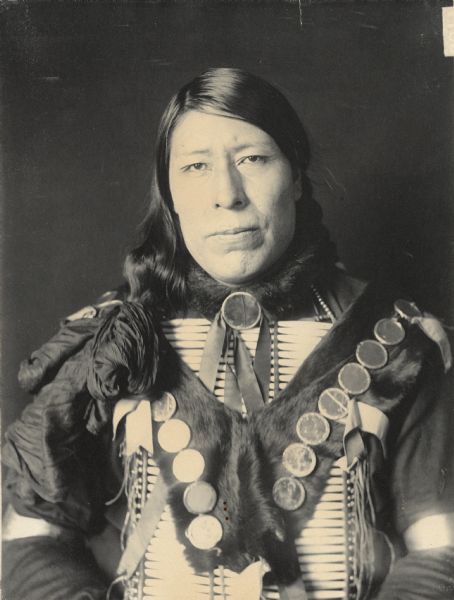 Portrait (Front) of Grabbing Bear in with breastplate. Part of Siouan (Sioux) and Brule Tribes