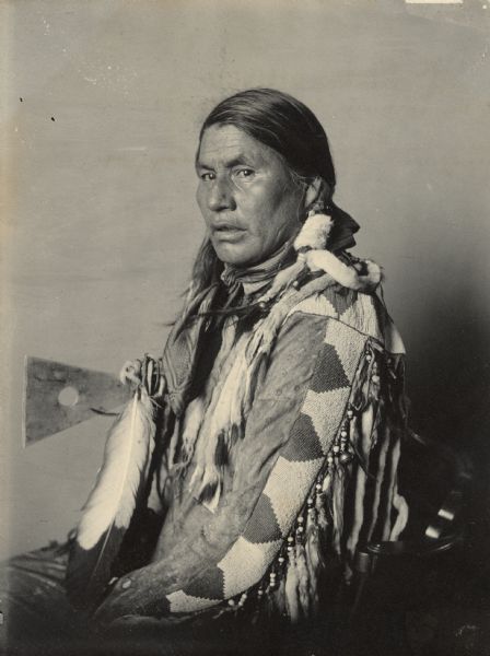 Portrait of I-Me-Tacco (Little Dog) in native Dress and holding a pipe-tomahawk. Part of Siouan (Sioux) and Blackfoot Tribes. He holds an axe.
