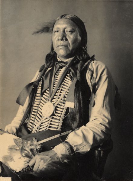 Portrait (Profile) of Ke-Wa-Ko (Good Fox) in partial native dress with peace medal, breastplate and ornaments and holding fan. Part of Caddoan and Pawnee Tribes.