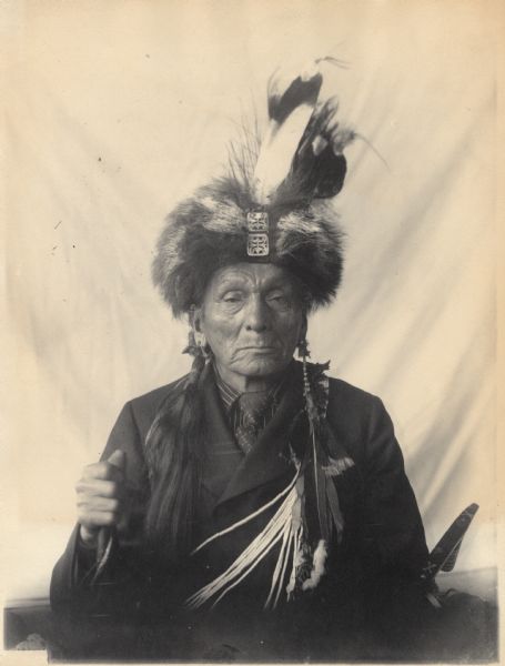 Portrait (Front) of Meshekigishig or Mezhukigizhik (Sky Striking The Earth) or (Sky Touching Ground) in partial native dress with headdress and ornaments and holding a pipe. Part of Algonquian and Chippewa Tribes.