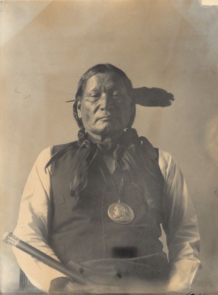 Portrait (Front) of Nawat (Left Hand) in native dress with Benjamin Harrison peace medal and holding cane. Part of Algonquian and S. Arapaho Tribes.