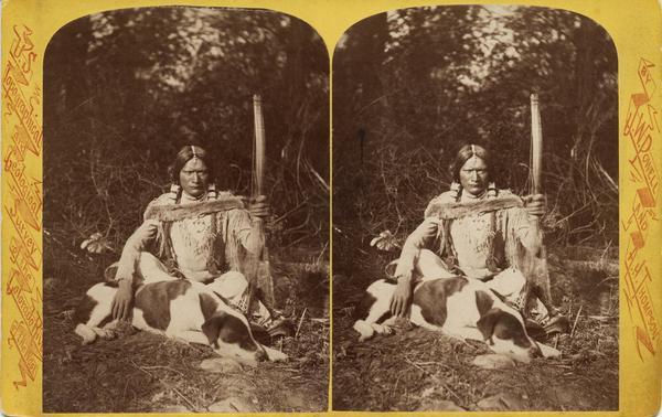Stereograph of a Native American man, a Ute Indian, seated with a dog.