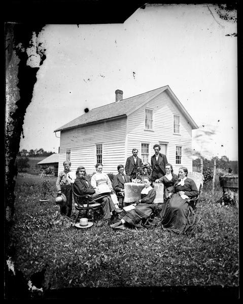 The Andrew Amundsen family is posing around a table adorned with a knit cloth. Andrew and his wife, Sarah, are in rocking chairs with cloths over the backs. Their frame house is behind them. The 1870 census listed the Andrew Amundsen family as consisting of Andrew, 52; Sarah, 45; Gjertrud, 18; Lausa, 15; Helena, 12; Lewis, 9; and Susania, 7.  Andreas Larsen Dahl married Gjertrud Amundsen, second from right, in August 1878.