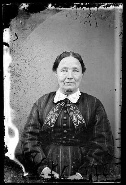 Waist-up portrait of an older woman wearing a Norwegian collar and a pin.