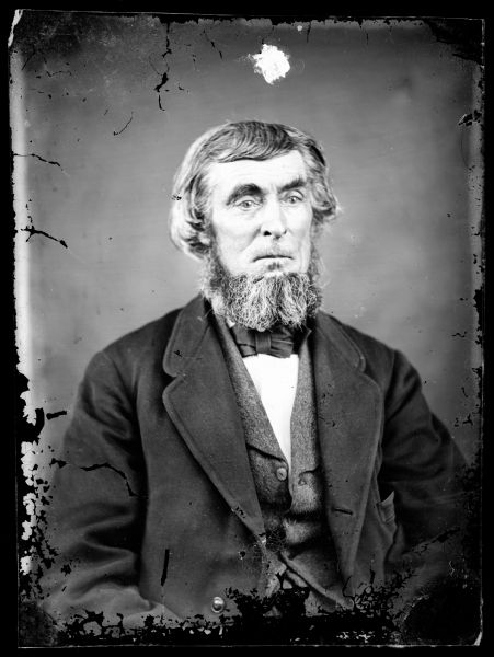 Portrait of a bearded man in a vest, bow tie, shirt and jacket.
