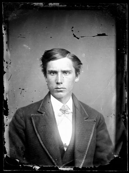 Portrait of a young man wearing a vest, shirt and jacket.