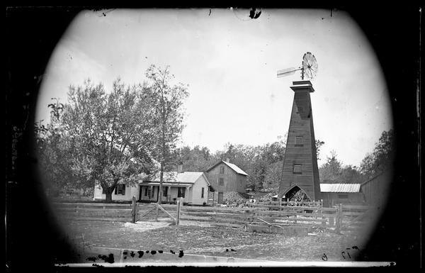 View of upright and wing house with adjacent windmill structure made in Batavia, Illinois, by U.S. Wind Eng. Pump Co. The barn has a stone foundation.