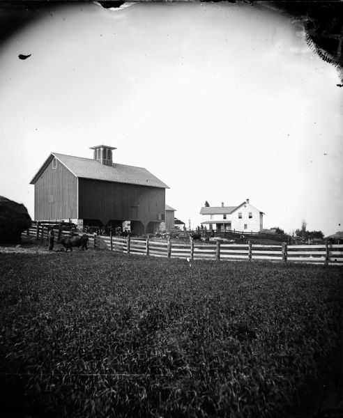In the foreground is a man with a cow and a haystack, with a family and a farmstead in the background. Walworth Co.