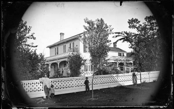 The Richard Green residence is a frame house with a porch that features latticework. Before it stands an elaborate white fence. A clothesline pole can be seen.  The man on the left is Richard Green. The boy standing by the tree is Burton E. Green, born 1868.  Green family moved to California in 1886.  Burton Green became a very wealthy developer of Hollywood California.
The Green House was moved to make way for the Pierstorff House.  
The Green House was cut in two (2 story front half & 1 story back half) and moved to 1719 & 1725 Henry St. Middleton.
The Pirestorff House, 7457 Terrace Ave., Middleton was restored and now (2023) is Restoring Hope Transplant House.