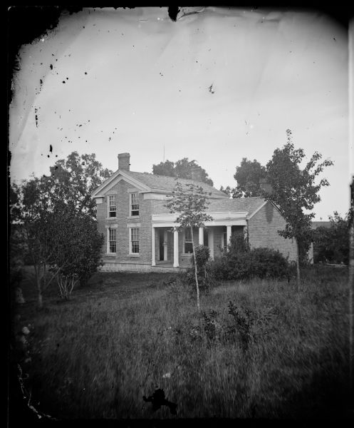 Greek Revival house with upright and wing configuration in rural setting.