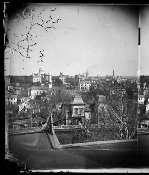 View, ca. 1873-1879, of Madison looking down Wisconsin Avenue toward the third Wisconsin Capitol, a view that suggests something of the ongoing importance of the Capitol building in the Madison urban landscape. The building that partially blocks the view of the Capitol is the U.S. Post Office. View from the William F. Vilas House on the corner of East Gilman and Wisconsin Avenue. Seen are the Capitol, City Hall and the Park Hotel. Entitled "Central View of the City from Yankee Hill" in Dahl's 1877 "Catalogue of Stereoscopic Views." From the series, "Views of the City of Madison, Wisconsin."