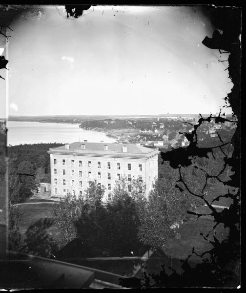 View from Main Hall (later Bascom Hall) on the University of Wisconsin campus.  North Hall is in the foreground.  Behind it is Langdon Street and, in the distance, the Capitol.  Lakes Mendota and Monona are both visible.