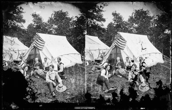 Boys outside tent that has sign, "Boys of the Hawthorne" above its door. This picture is identified as the Chicago Traveling Club's trip #8.