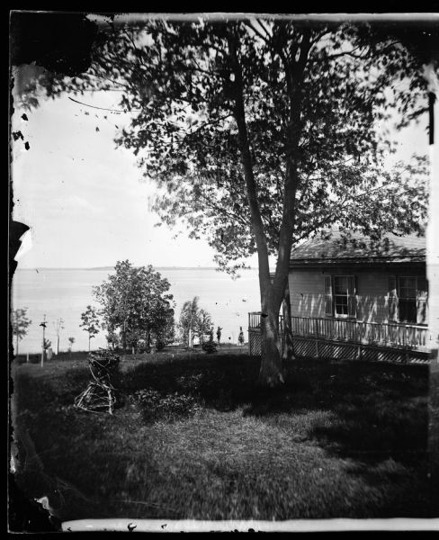 Partial view of billiard hall and Lake Mendota from the Ole Bull Residence, 130 East Gilman Street. Two people on shore are pointing to a sailboat. Later, the house was known as the Thorp House. It became the executive mansion for the governor of Wisconsin in 1885 and the University of Wisconsin Knapp Graduate Center after 1950.