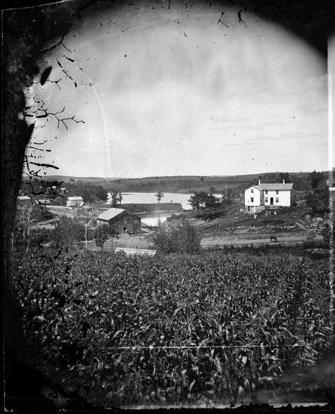 View, through a cornfield, of people, a store, a sawmill and wagons.  Moscow was platted in 1850 by an Englishman, Chauncy Smith, who dammed the Bluemound branch of the Pecatonica River to run a grist mill. It was settled by English, Irish, German and Norwegian immigrants.