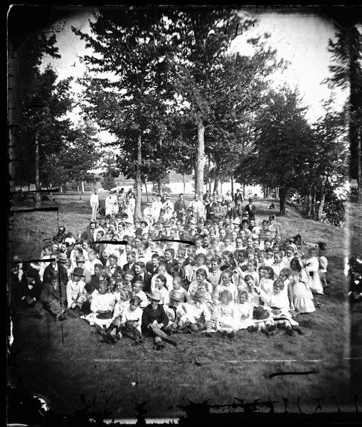 Large picnic group, mainly children, at lakeshore, possibly McBride's Point in Maple Bluff on Lake Mendota near Madison.