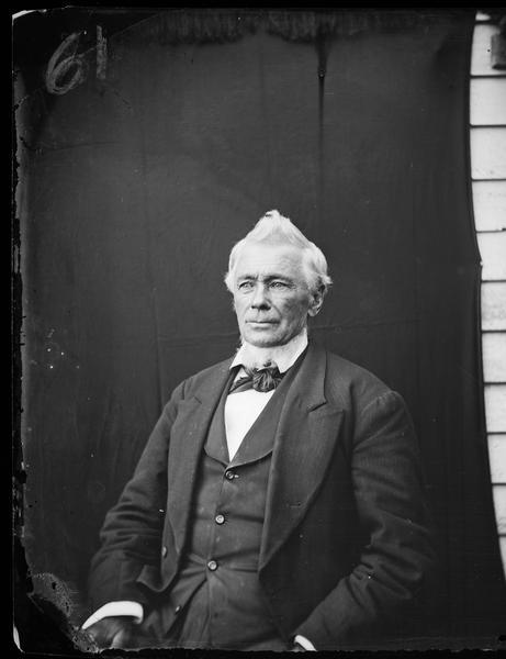 Waist-up portrait of Mr. Beaty photographed out-of-doors against a dark backdrop.