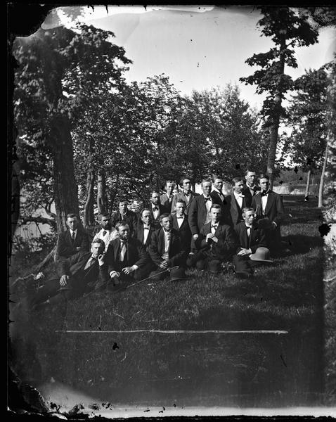 A group portrait of a well-dressed group of young men with hats and canes outdoors.  They may be at Maple Bluff on Lake Mendota near Madison.