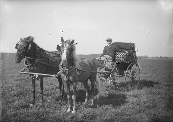 Walter in carriage wearing hat, with blanket covering.