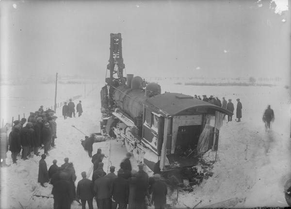 Elevated view of people standing around the engine of "Soo Line" wreck in winter.
