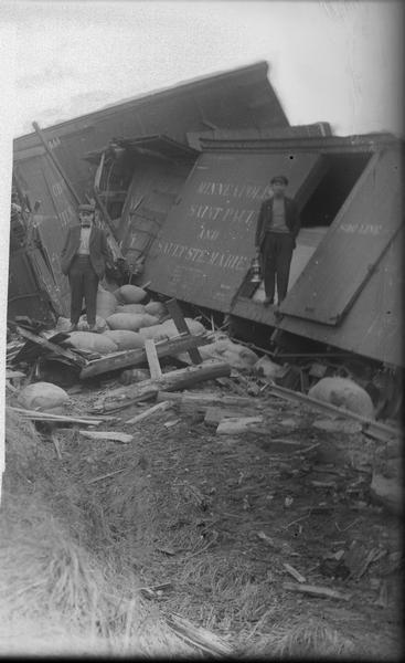 Soo Line train wreck, with two men standing near box car wreckage.