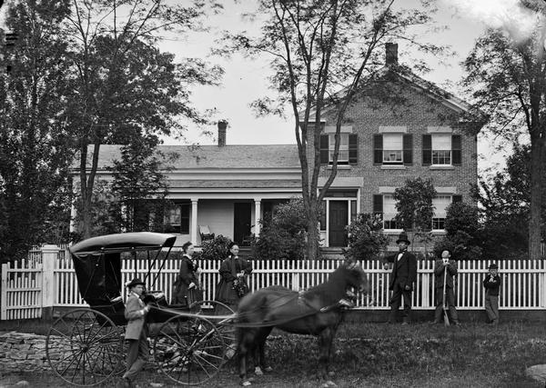An unidentified family proudly posed in front of their brick, Greek Revival home, with their carriage and team of horses. Although the location is unidentified, the fact that the image is part of Dahl collection suggests that it is Dane County.