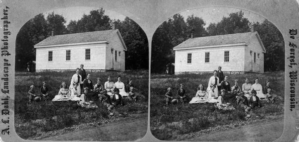 Students and teachers sitting in front of the Blue Mounds school house.