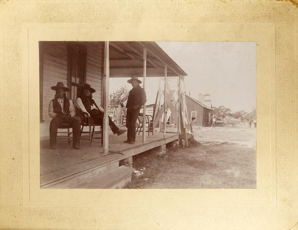 Men gather on a porch of the Ponca Agency Building.
