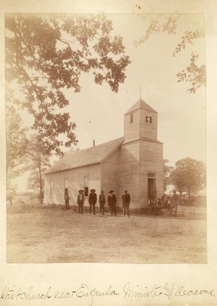 A minister and deacons in front of a Baptist Church.