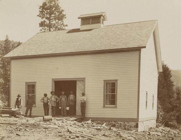 A group of workers stand in the doorway of a new stable at the Greenville Indian School.