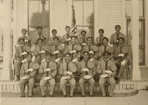 A group of Pima Agency male students in front of an agency building.