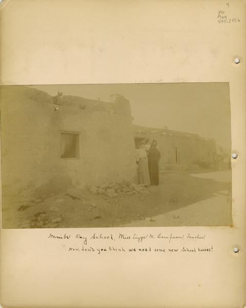 A page from an album of photographs of Pueblo Indian Day Schools, showing the Nambe Day School.  Miss Lizzie M. Lampson, the teacher, gathers with others near the door.